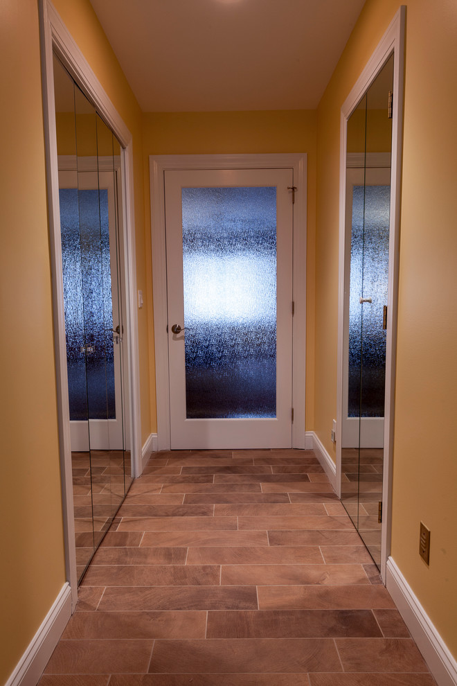 Imagen de cuarto de baño principal contemporáneo grande con lavabo sobreencimera, armarios con paneles lisos, puertas de armario de madera en tonos medios, encimera de ónix, bañera exenta, ducha esquinera, sanitario de dos piezas, baldosas y/o azulejos beige, baldosas y/o azulejos de porcelana, paredes amarillas y suelo de baldosas de porcelana