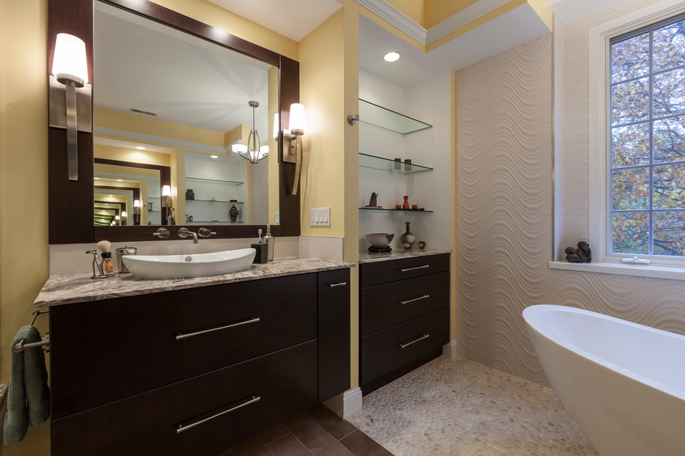 Exemple d'une grande salle de bain principale tendance en bois foncé avec une vasque, un placard à porte plane, un plan de toilette en onyx, une baignoire indépendante, une douche d'angle, WC séparés, un carrelage beige, des carreaux de porcelaine, un mur jaune et un sol en carrelage de porcelaine.