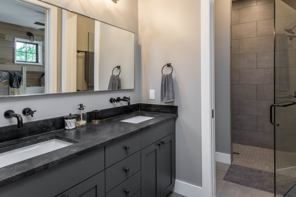 This is an example of a medium sized rustic ensuite bathroom in Other with shaker cabinets, brown cabinets, an alcove shower, a two-piece toilet, beige tiles, mosaic tiles, beige walls, porcelain flooring, soapstone worktops, beige floors, black worktops and a submerged sink.