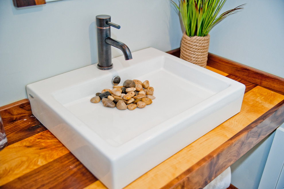 Diseño de cuarto de baño actual, pequeño, con lavabo sobreencimera, encimera de madera, sanitario de una pieza, paredes grises, suelo de madera en tonos medios y aseo y ducha