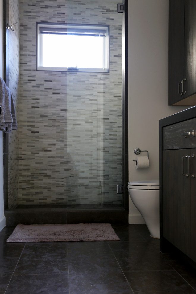 Medium sized urban family bathroom in San Diego with flat-panel cabinets, grey cabinets, marble worktops, multi-coloured tiles, stone tiles, an alcove bath, a shower/bath combination, a two-piece toilet, a submerged sink, white walls and limestone flooring.