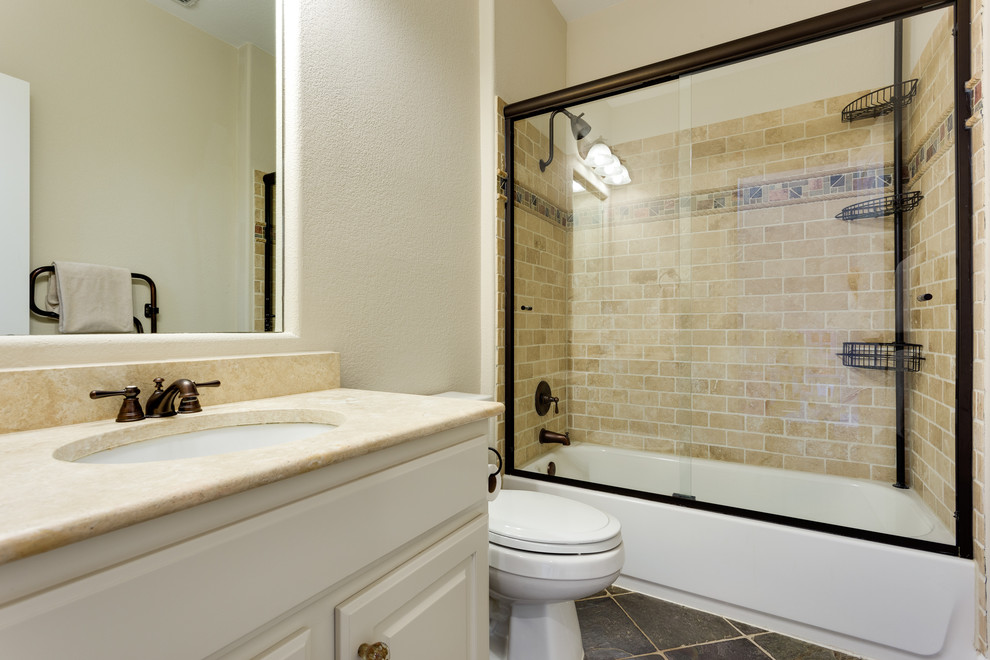 Идея дизайна: ванная комната среднего размера в современном стиле с фасадами с выступающей филенкой, белыми фасадами, душем над ванной, бежевой плиткой, плиткой из известняка, бежевыми стенами, полом из цементной плитки, столешницей из гранита, серым полом и душем с раздвижными дверями