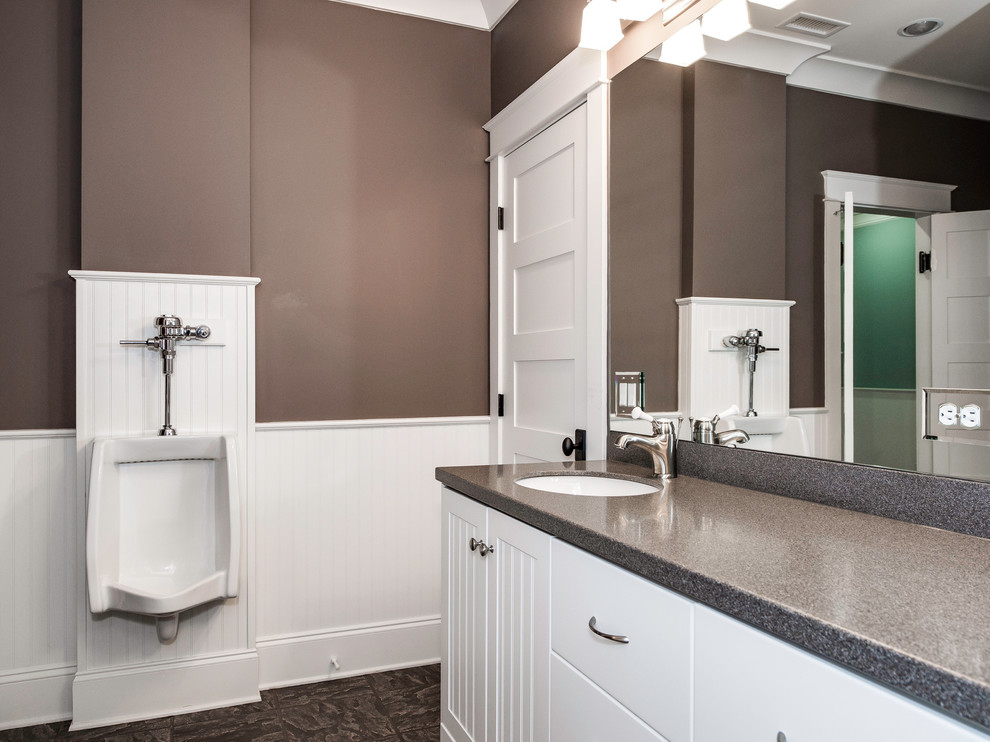 Foto på ett amerikanskt badrum för barn, med luckor med profilerade fronter, vita skåp, ett urinoar, brun kakel, porslinskakel, bruna väggar, klinkergolv i porslin och bänkskiva i akrylsten