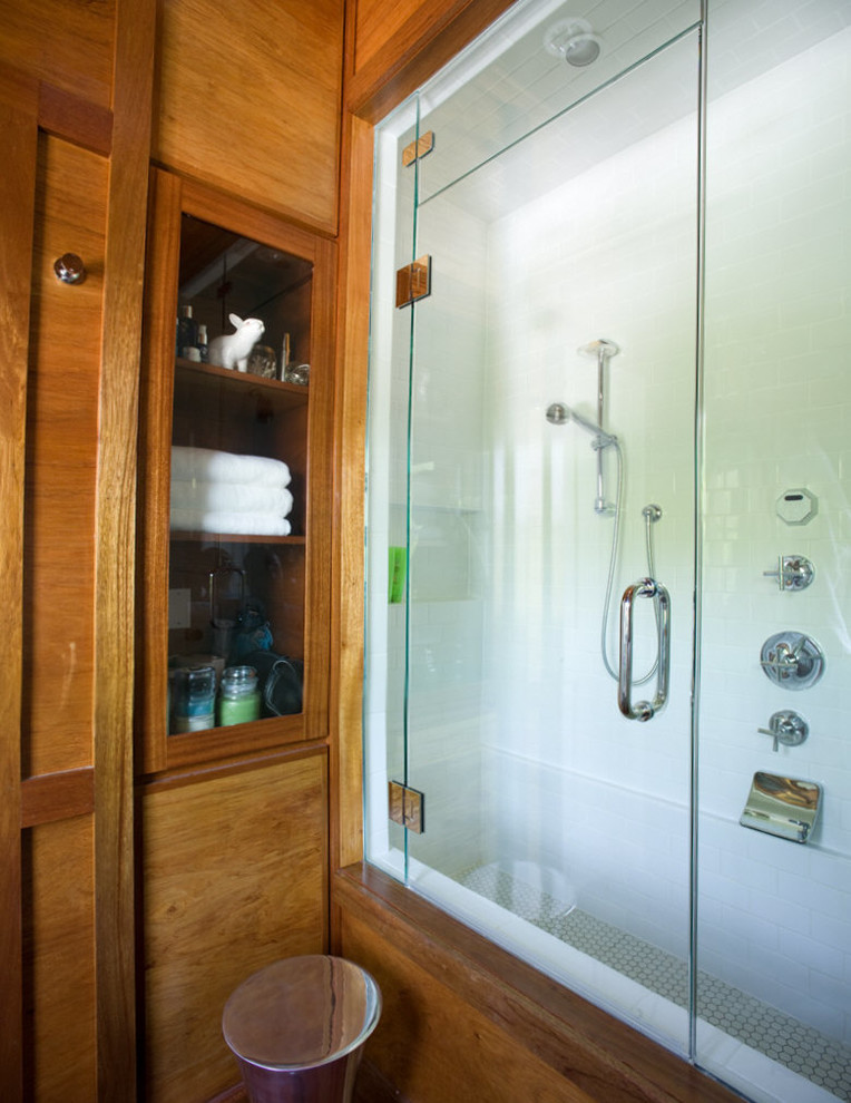 Modelo de cuarto de baño clásico renovado con armarios con paneles lisos, puertas de armario de madera oscura, encimera de madera, combinación de ducha y bañera y suelo de madera en tonos medios