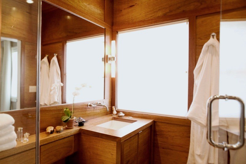 Immagine di una stanza da bagno chic con ante lisce, ante in legno scuro, top in legno, vasca/doccia e pavimento in legno massello medio