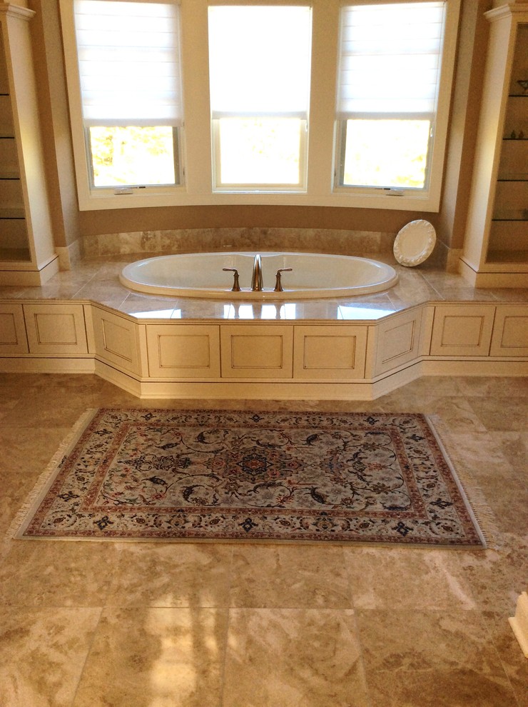 Idée de décoration pour une grande salle de bain principale méditerranéenne en bois clair avec un placard avec porte à panneau encastré, un plan de toilette en marbre, une baignoire posée, un carrelage beige, un carrelage de pierre, un mur marron et un sol en marbre.