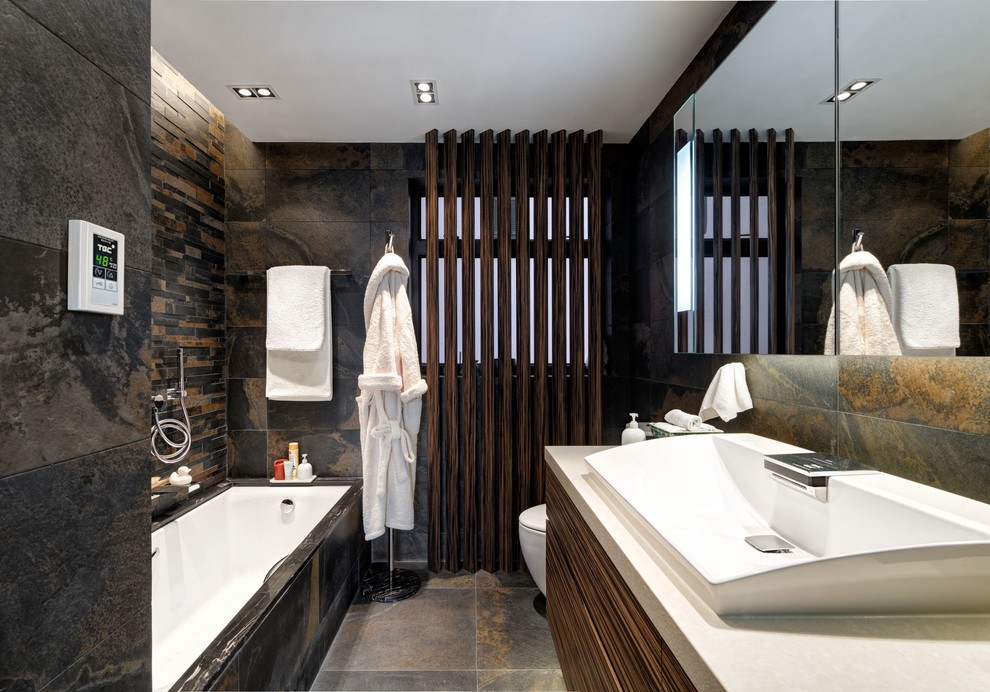 Imagen de cuarto de baño de estilo zen con lavabo sobreencimera, bañera empotrada y baldosas y/o azulejos de piedra
