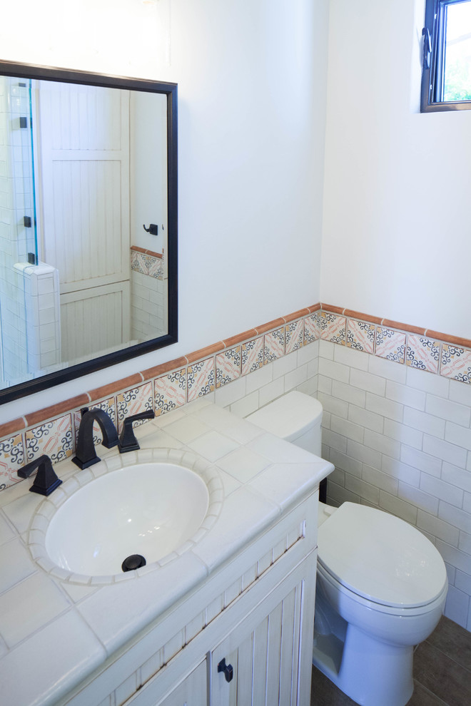 Идея дизайна: маленькая ванная комната в стиле фьюжн с бежевыми фасадами, угловым душем, унитазом-моноблоком, бежевой плиткой, терракотовой плиткой, бежевыми стенами, полом из керамогранита, душевой кабиной, врезной раковиной, столешницей из плитки, коричневым полом, душем с распашными дверями, бежевой столешницей и фасадами с утопленной филенкой для на участке и в саду