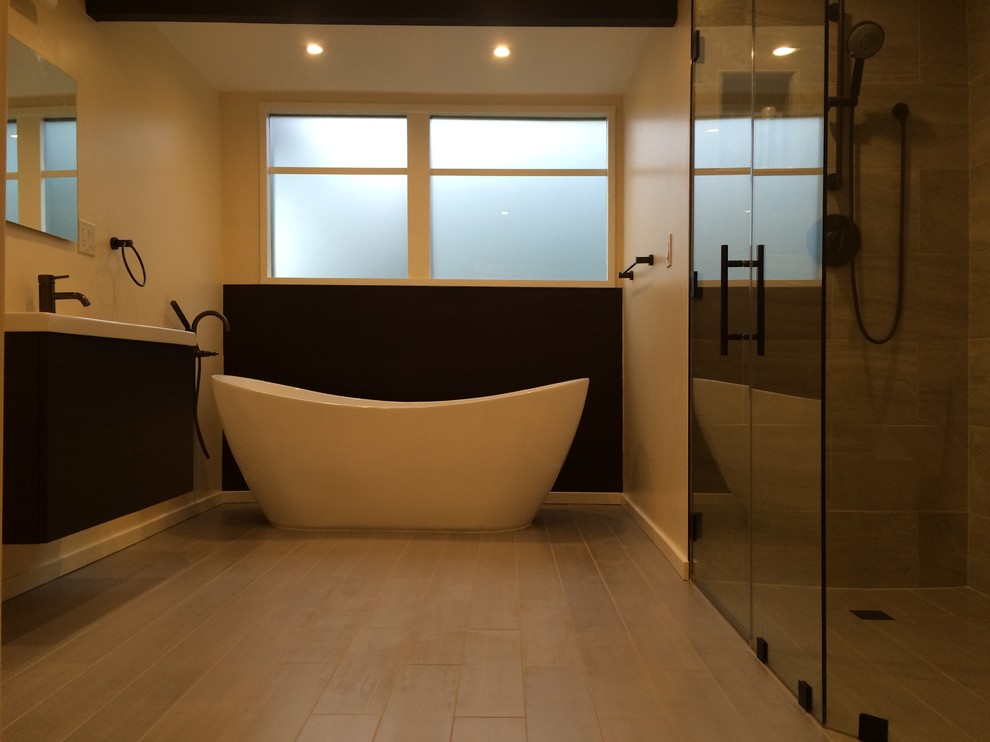 Exempel på ett stort modernt en-suite badrum, med släta luckor, svarta skåp, ett platsbyggt badkar, en toalettstol med hel cisternkåpa, beige kakel, stenkakel, klinkergolv i keramik, ett undermonterad handfat och granitbänkskiva