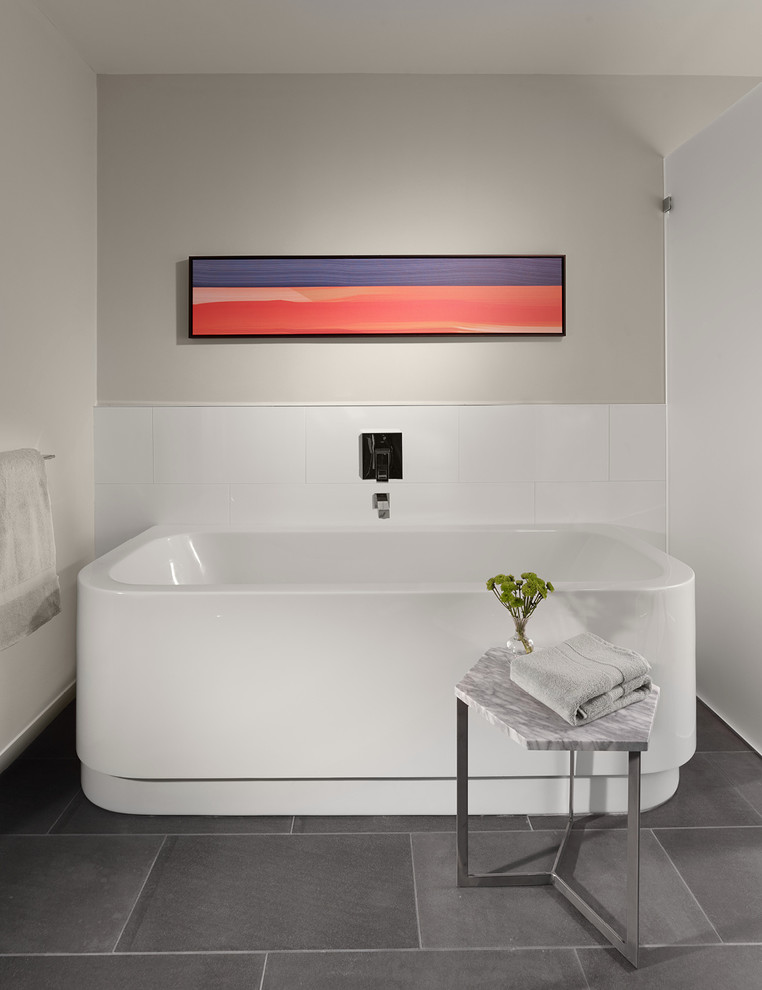 Modelo de cuarto de baño rectangular actual grande con bañera exenta, baldosas y/o azulejos blancos, suelo de pizarra y paredes grises