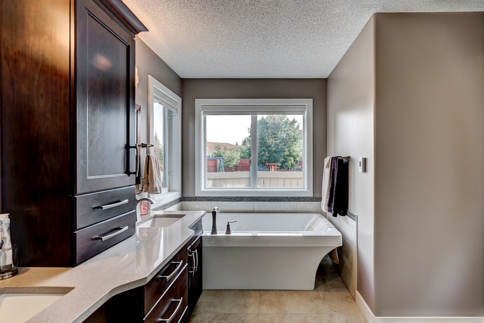 Example of a mid-sized freestanding bathtub design in Edmonton with recessed-panel cabinets, dark wood cabinets and brown walls