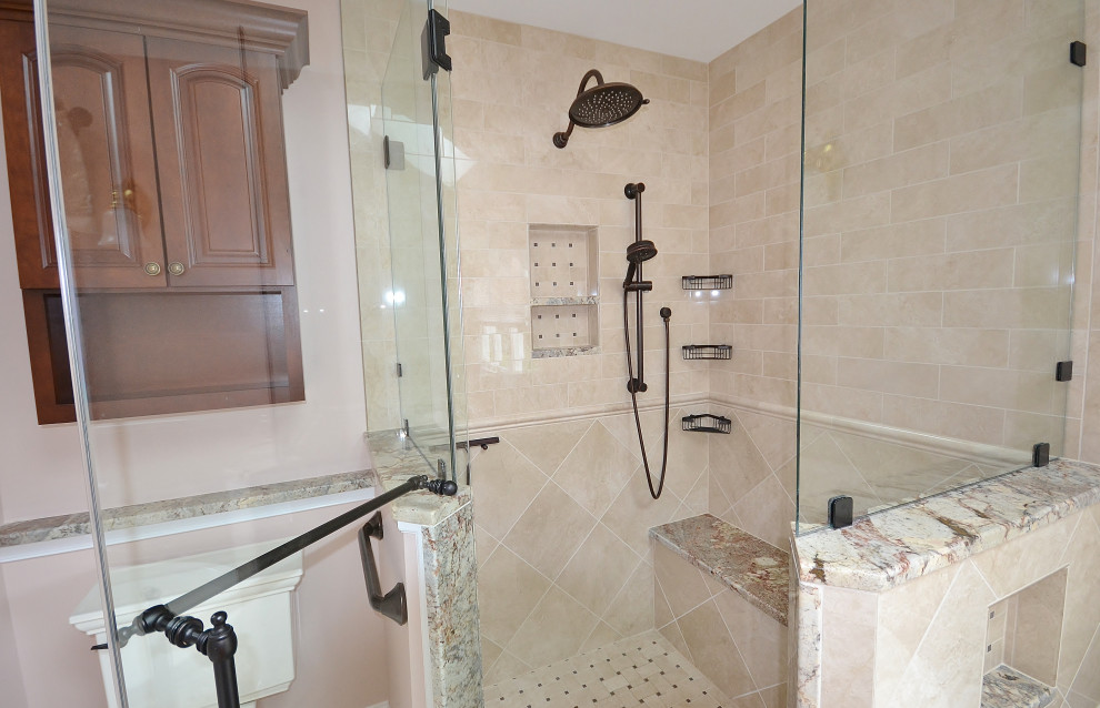 Пример оригинального дизайна: большая главная ванная комната в стиле неоклассика (современная классика) с фасадами с утопленной филенкой, темными деревянными фасадами, накладной ванной, угловым душем, унитазом-моноблоком, бежевой плиткой, керамической плиткой, розовыми стенами, полом из керамической плитки, врезной раковиной, столешницей из гранита, бежевым полом, душем с распашными дверями, разноцветной столешницей, сиденьем для душа, тумбой под две раковины, встроенной тумбой и сводчатым потолком