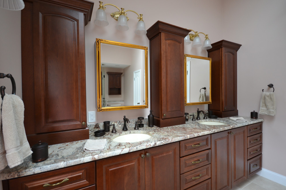 Идея дизайна: большая главная ванная комната в стиле неоклассика (современная классика) с фасадами с утопленной филенкой, темными деревянными фасадами, накладной ванной, угловым душем, унитазом-моноблоком, бежевой плиткой, керамической плиткой, розовыми стенами, полом из керамической плитки, врезной раковиной, столешницей из гранита, бежевым полом, душем с распашными дверями, разноцветной столешницей, сиденьем для душа, тумбой под две раковины, встроенной тумбой и сводчатым потолком
