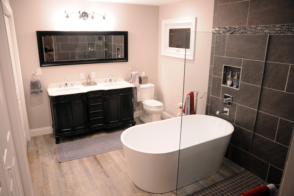 Пример оригинального дизайна: большая главная ванная комната в стиле модернизм с фасадами островного типа, черными фасадами, отдельно стоящей ванной, угловым душем, раздельным унитазом, черной плиткой, серой плиткой, плиткой из сланца, коричневыми стенами, паркетным полом среднего тона, врезной раковиной, коричневым полом и открытым душем