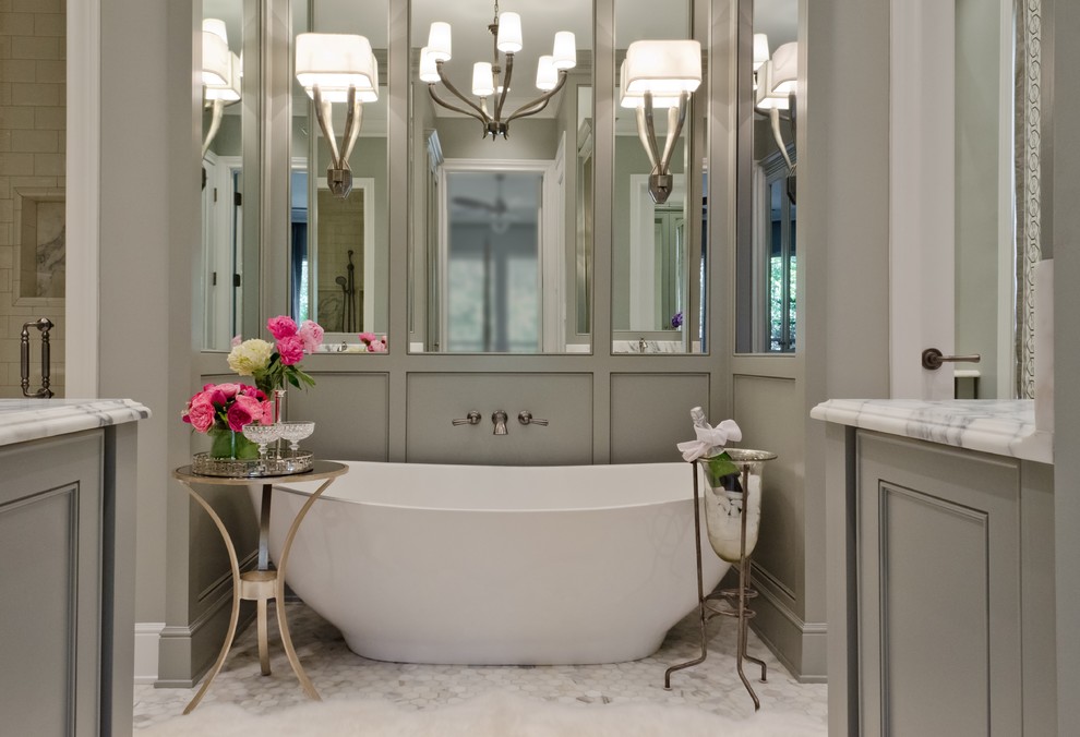 Inredning av ett klassiskt en-suite badrum, med ett undermonterad handfat, ett fristående badkar, en dusch i en alkov, grå väggar, marmorgolv, luckor med infälld panel, grå skåp, marmorbänkskiva och vit kakel