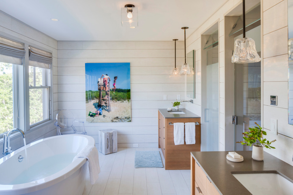 Esempio di una stanza da bagno padronale costiera con ante lisce, ante in legno chiaro, vasca freestanding, pareti bianche, lavabo sottopiano, pavimento bianco e top grigio