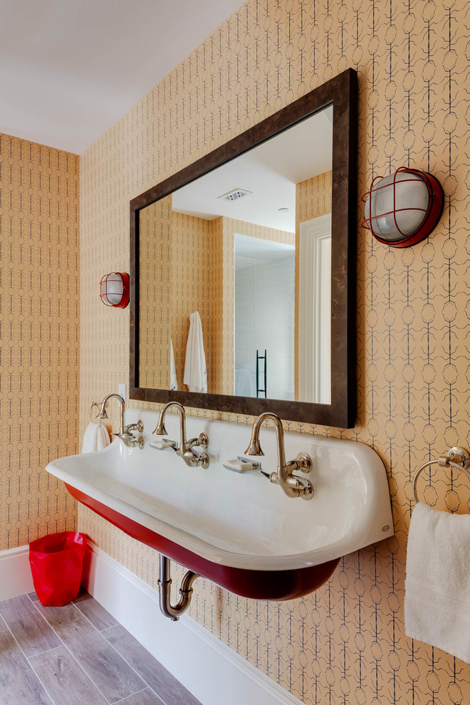 Пример оригинального дизайна: ванная комната в морском стиле с оранжевыми стенами, раковиной с несколькими смесителями и серым полом