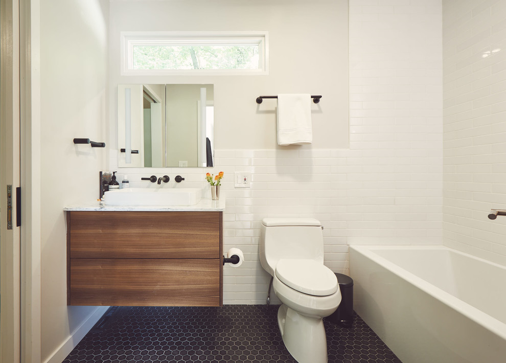 На фото: маленькая главная ванная комната в современном стиле с плоскими фасадами, коричневыми фасадами, ванной в нише, душем над ванной, унитазом-моноблоком, белой плиткой, керамической плиткой, серыми стенами, полом из керамической плитки, настольной раковиной, мраморной столешницей, черным полом, шторкой для ванной и белой столешницей для на участке и в саду