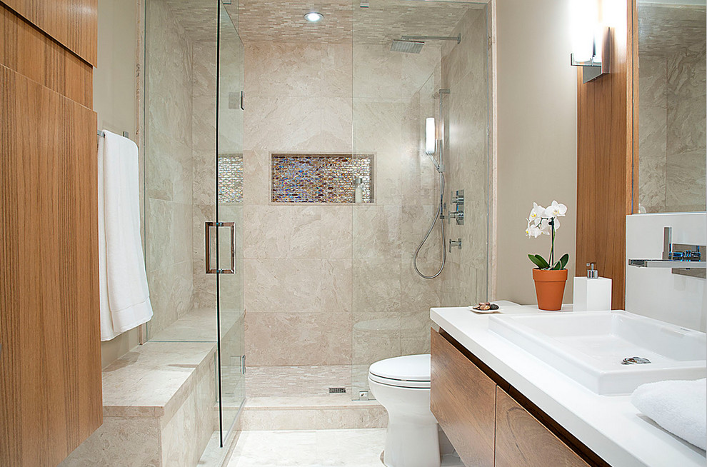 Modernes Badezimmer mit flächenbündigen Schrankfronten, hellen Holzschränken, Mineralwerkstoff-Waschtisch, Duschnische, Toilette mit Aufsatzspülkasten und Travertin in Toronto