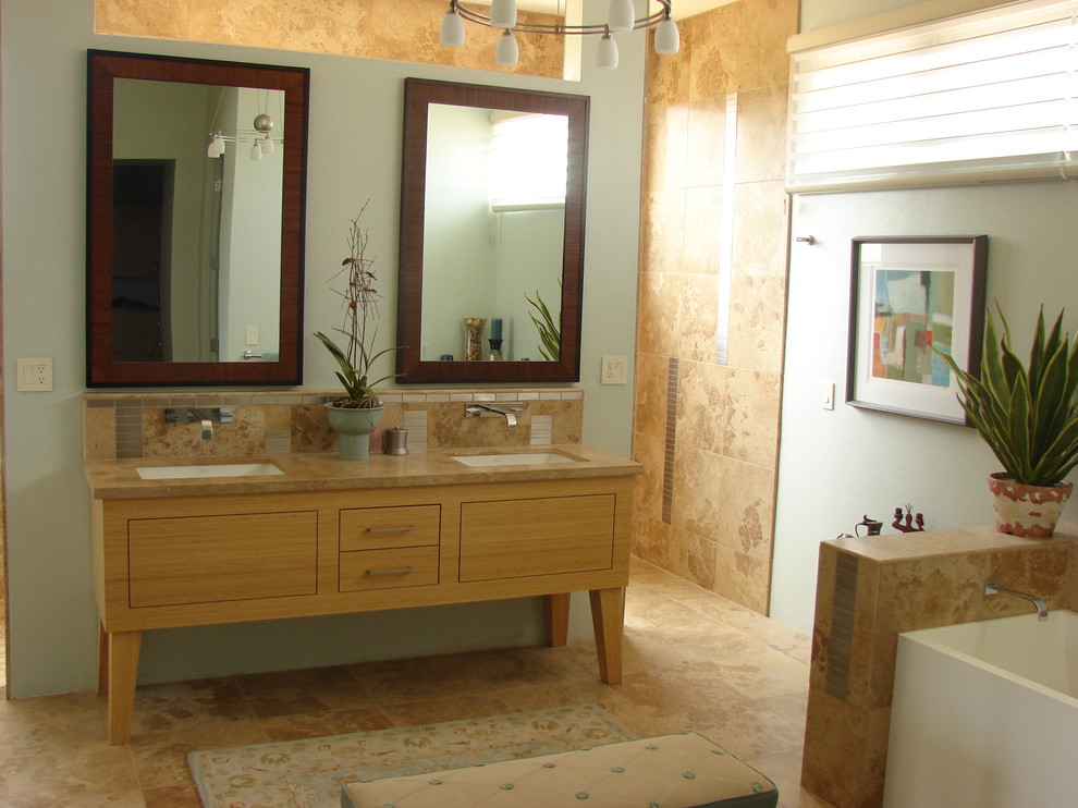 Idee per una grande stanza da bagno padronale design con ante lisce, ante in legno chiaro, vasca da incasso, pareti beige, pavimento in pietra calcarea, lavabo integrato e top in marmo
