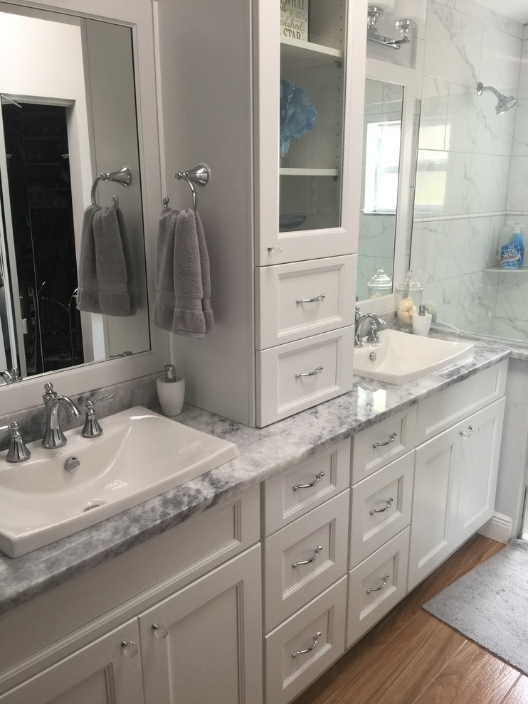 Diseño de cuarto de baño principal clásico renovado de tamaño medio con armarios con paneles empotrados, puertas de armario blancas, ducha empotrada, paredes grises, suelo de madera clara, lavabo sobreencimera y encimera de mármol