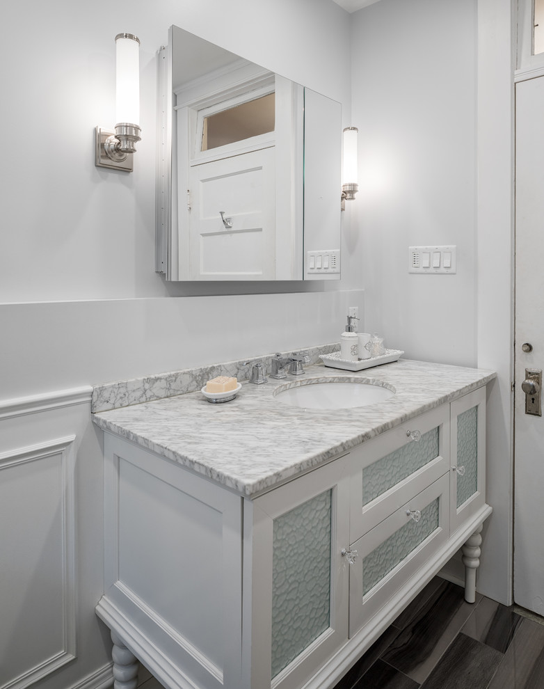 Example of a mid-sized transitional 3/4 gray tile, white tile and marble tile porcelain tile and gray floor alcove shower design in Ottawa with glass-front cabinets, white cabinets, white walls, an undermount sink, marble countertops and a hinged shower door