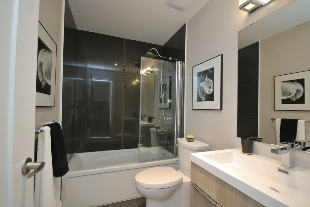Idée de décoration pour une salle de bain minimaliste en bois clair de taille moyenne avec un placard à porte plane, une baignoire posée, un combiné douche/baignoire, WC séparés, un carrelage gris, des carreaux de porcelaine, un mur gris, un sol en carrelage de porcelaine, une grande vasque et un plan de toilette en granite.