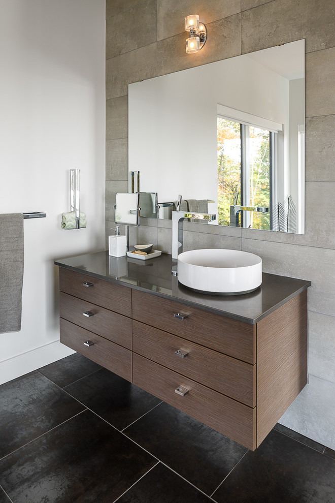 Cette photo montre une grande salle de bain principale tendance en bois foncé avec une vasque, un placard à porte plane, un carrelage gris et un mur blanc.