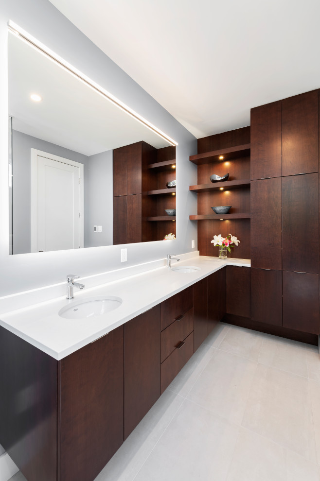 Diseño de cuarto de baño doble contemporáneo con armarios con paneles lisos, puertas de armario de madera en tonos medios, paredes grises, lavabo bajoencimera, suelo blanco, encimeras blancas y espejo con luz