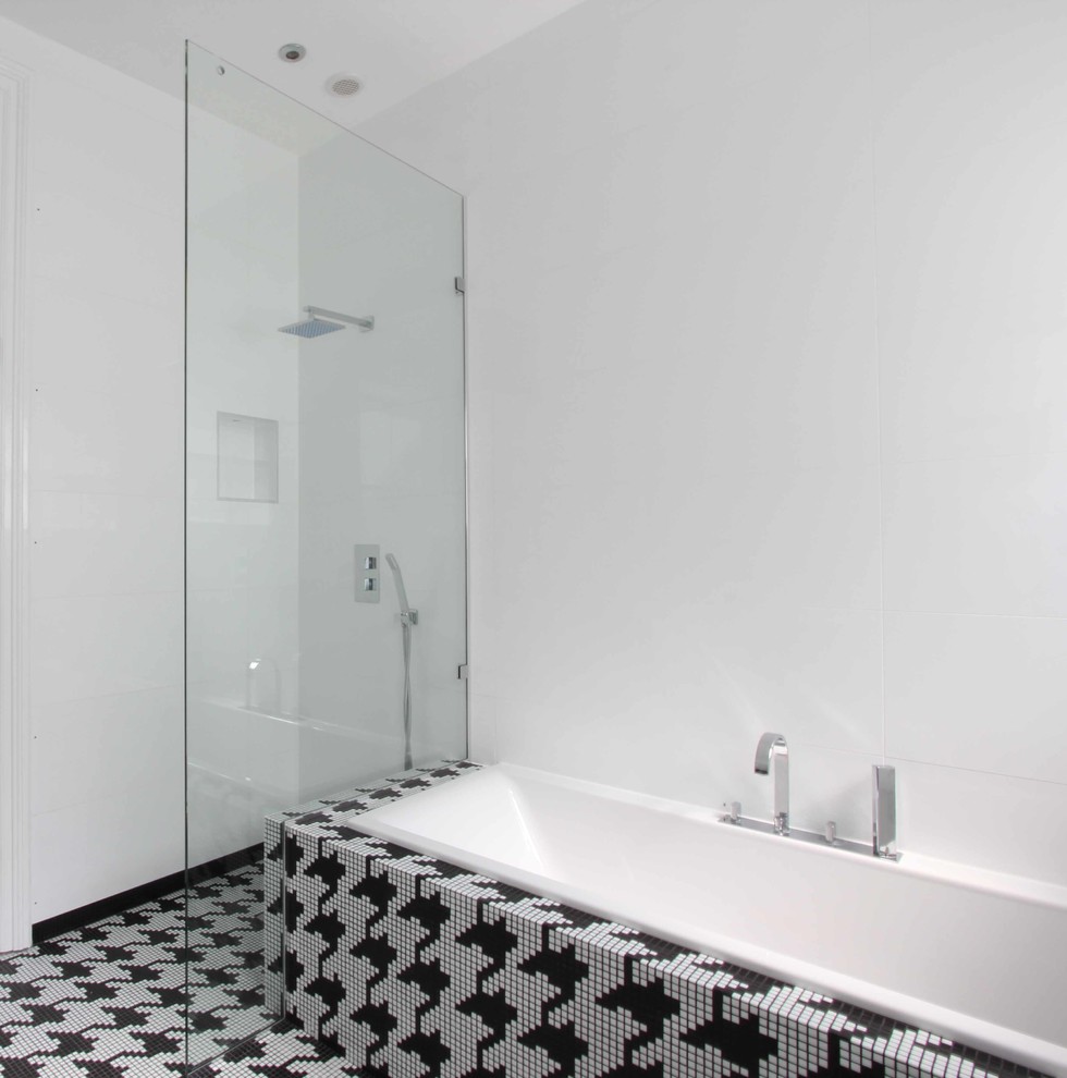 Example of a mid-sized trendy black tile and mosaic tile mosaic tile floor corner shower design in London with an undermount tub, a wall-mount toilet and white walls