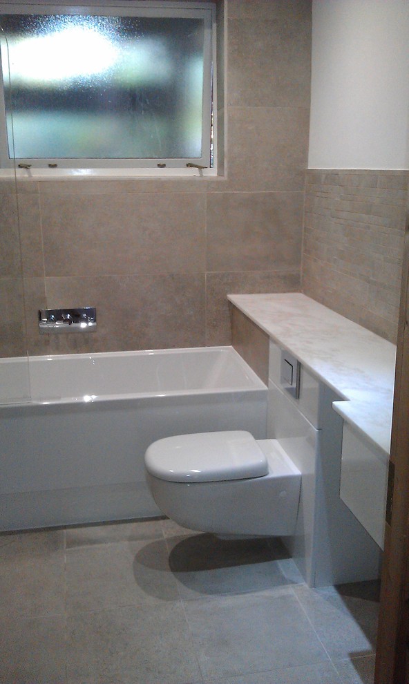 This is an example of a contemporary bathroom in London with a freestanding bath, a two-piece toilet, ceramic tiles and grey walls.