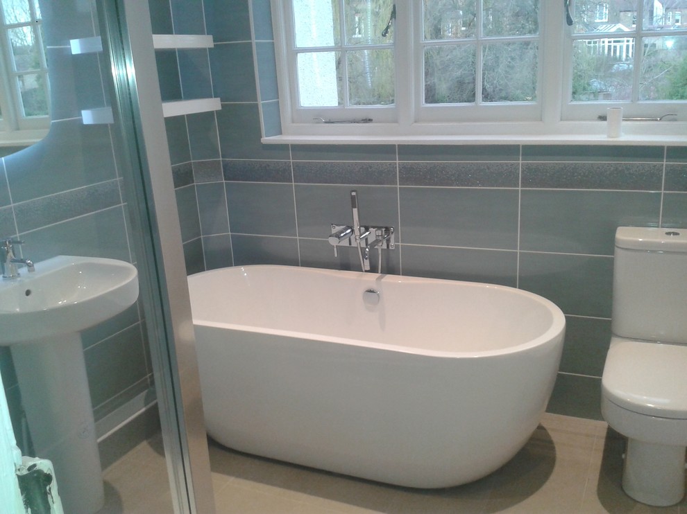 Inspiration för moderna badrum, med ett fristående badkar, en toalettstol med separat cisternkåpa, keramikplattor och grå väggar