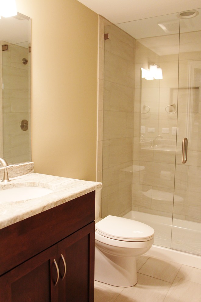 Modelo de cuarto de baño clásico de tamaño medio con armarios estilo shaker, puertas de armario de madera en tonos medios, encimera de granito, baldosas y/o azulejos beige y aseo y ducha