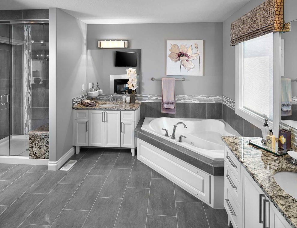 Medium sized traditional ensuite bathroom in Edmonton with raised-panel cabinets, white cabinets, a built-in bath, an alcove shower, a two-piece toilet, black and white tiles, grey tiles, white tiles, matchstick tiles, grey walls, a submerged sink, granite worktops, a hinged door and grey floors.