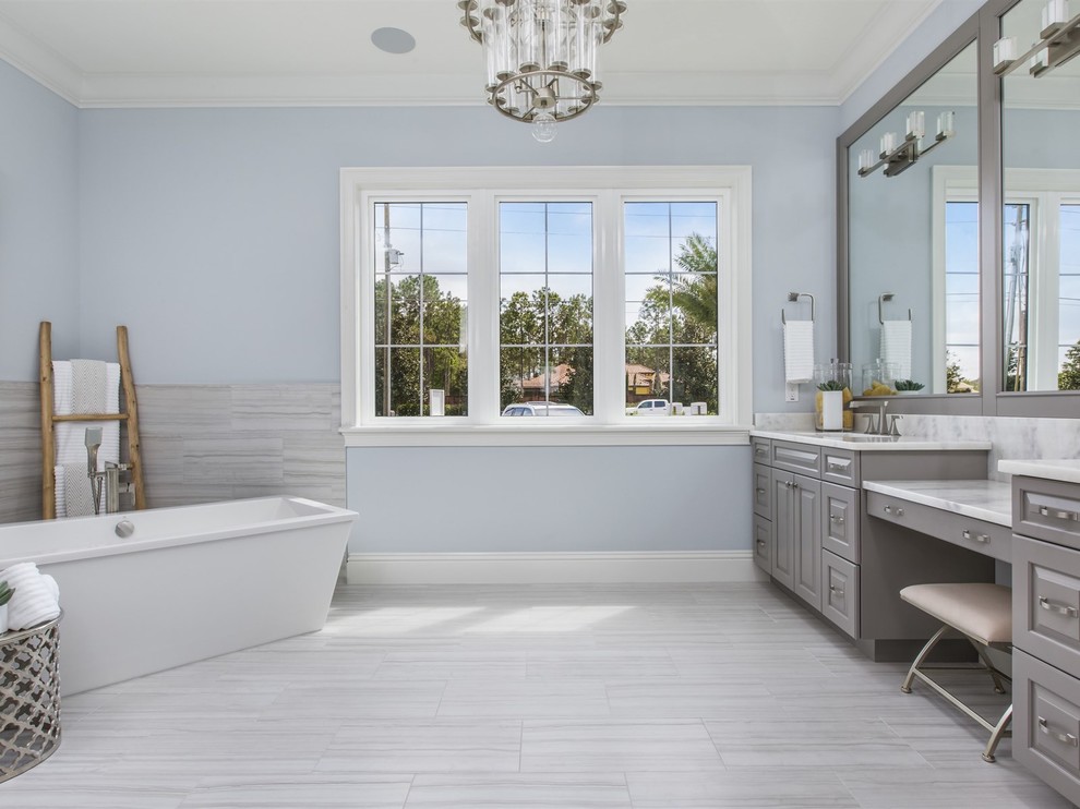 На фото: большая главная ванная комната в стиле неоклассика (современная классика) с серыми фасадами, отдельно стоящей ванной, серой плиткой, керамогранитной плиткой, фасадами с выступающей филенкой, душем в нише, унитазом-моноблоком, синими стенами, полом из керамогранита, врезной раковиной и мраморной столешницей