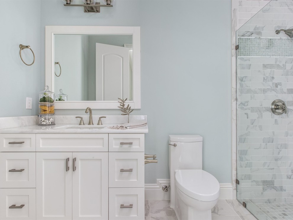 This is an example of a large traditional bathroom in Orlando with shaker cabinets, white cabinets, porcelain tiles, an alcove shower, a one-piece toilet, blue walls, marble flooring, a submerged sink and marble worktops.
