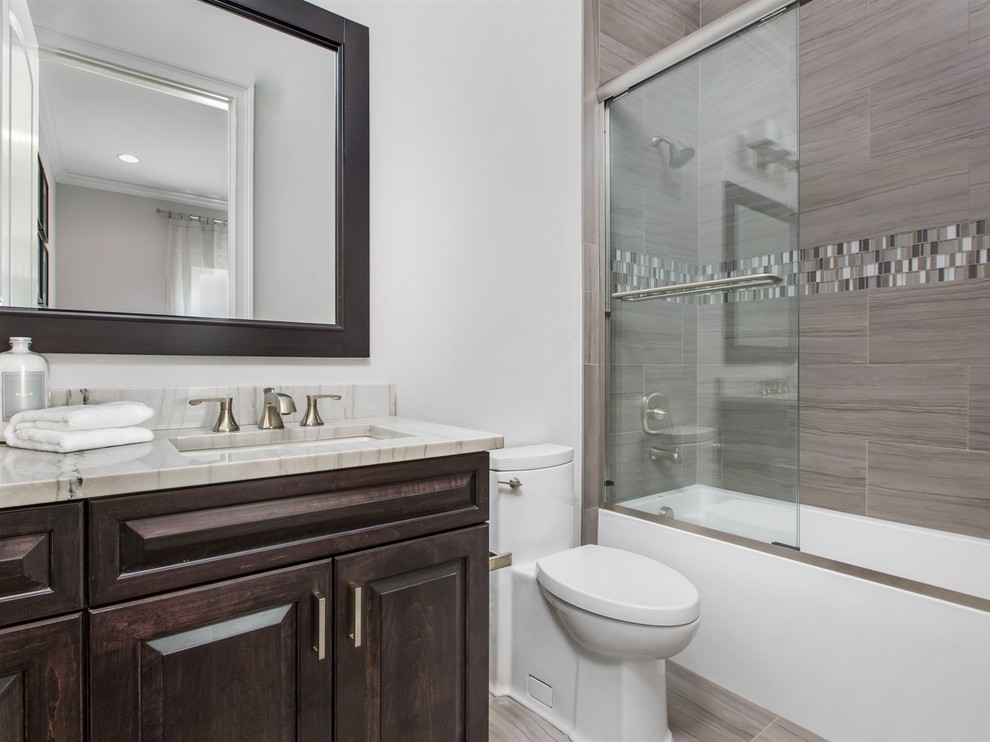Mid-sized transitional 3/4 gray tile and porcelain tile porcelain tile bathroom photo in Orlando with raised-panel cabinets, dark wood cabinets, a one-piece toilet, white walls, an undermount sink and granite countertops