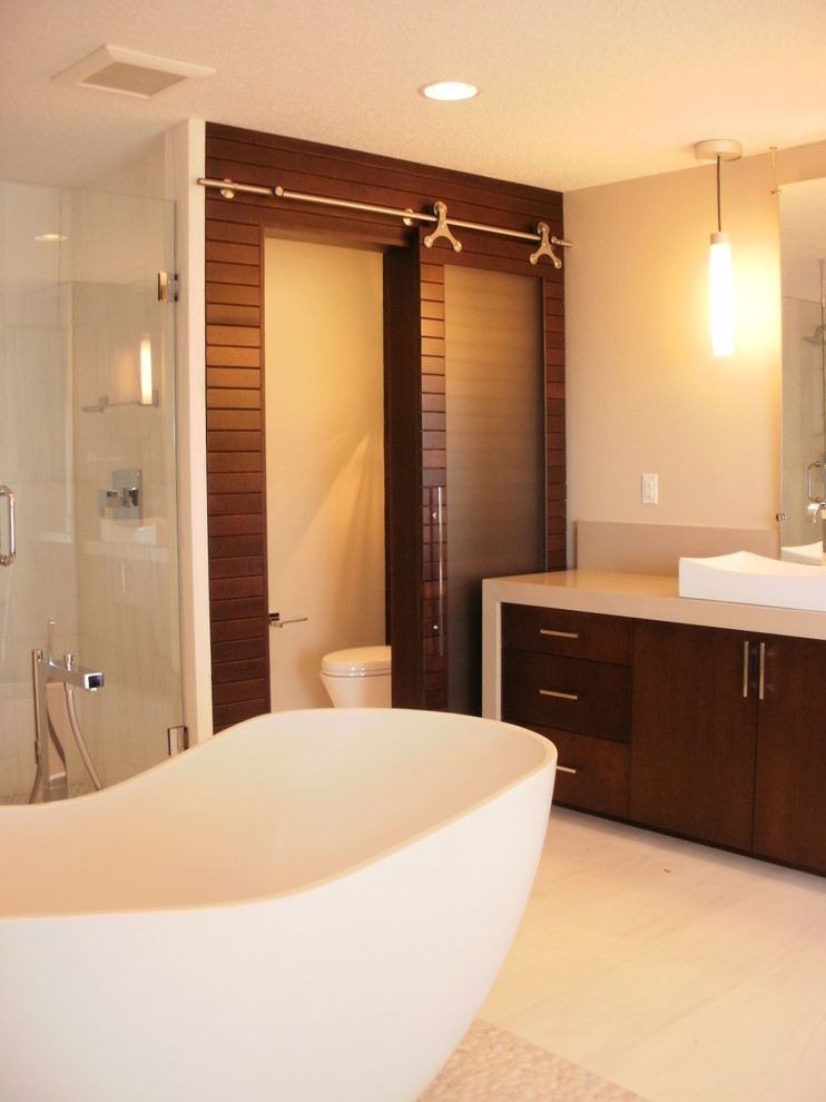 Inspiration för mellanstora moderna en-suite badrum, med ett fristående handfat, släta luckor, skåp i mörkt trä, ett fristående badkar, beige kakel och beige väggar