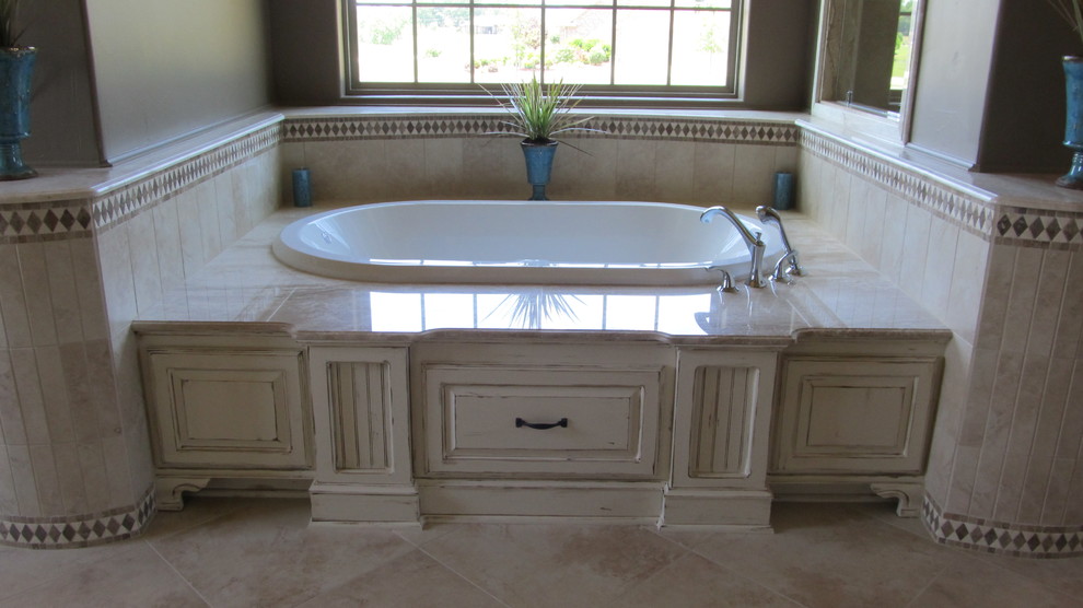 Design ideas for a large romantic ensuite bathroom in San Diego with a built-in bath, beige tiles, stone tiles, beige walls, limestone flooring, raised-panel cabinets, distressed cabinets and limestone worktops.