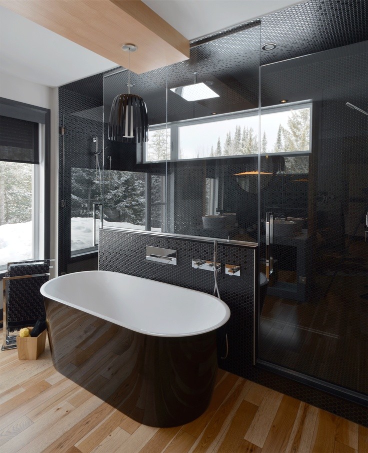 Imagen de cuarto de baño principal moderno grande con lavabo bajoencimera, armarios con paneles lisos, bañera exenta, baldosas y/o azulejos negros y suelo de madera clara
