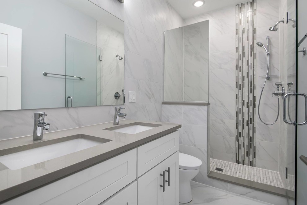 Photo of a medium sized contemporary ensuite bathroom in Chicago with shaker cabinets, white cabinets, an alcove shower, a two-piece toilet, grey tiles, porcelain tiles, grey walls, porcelain flooring, a submerged sink, engineered stone worktops, grey floors and a hinged door.