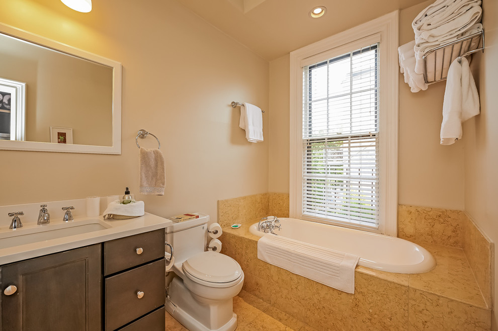 Пример оригинального дизайна: маленькая ванная комната в классическом стиле с плоскими фасадами, черными фасадами, накладной ванной, унитазом-моноблоком, желтой плиткой, белыми стенами, полом из травертина, врезной раковиной, столешницей из искусственного камня, душевой кабиной и бежевым полом для на участке и в саду