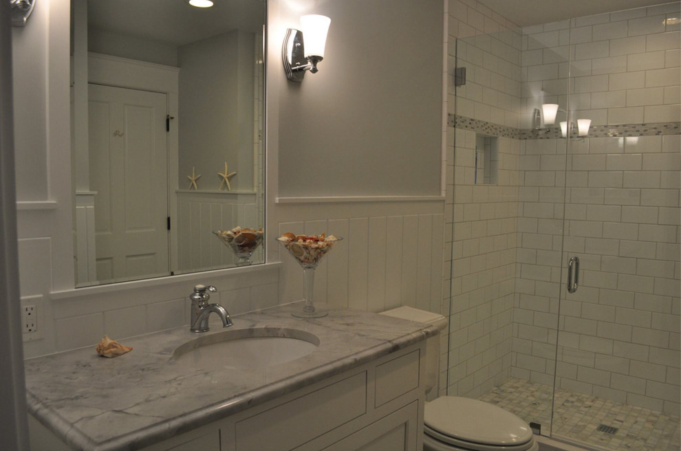Inredning av ett modernt mellanstort badrum med dusch, med luckor med infälld panel, vita skåp, en dusch i en alkov, en toalettstol med separat cisternkåpa, vit kakel, tunnelbanekakel, grå väggar, plywoodgolv, ett undermonterad handfat och marmorbänkskiva