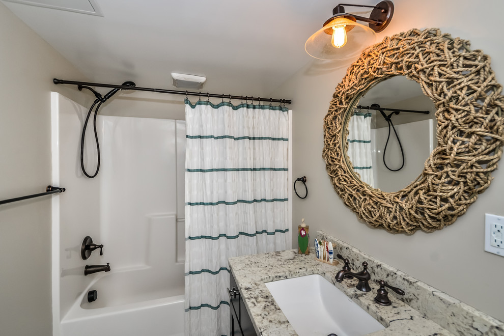 Idée de décoration pour une salle de bain marine en bois foncé de taille moyenne avec un placard à porte shaker, une baignoire en alcôve, un mur beige, un sol en carrelage de porcelaine, un lavabo encastré et un plan de toilette en granite.