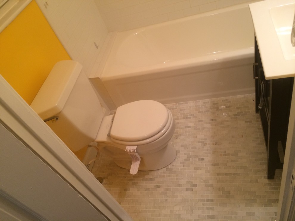 This is an example of a medium sized contemporary shower room bathroom in Orange County with freestanding cabinets, black cabinets, an alcove bath, a shower/bath combination, a two-piece toilet, yellow walls, marble flooring, an integrated sink, engineered stone worktops, white floors and a shower curtain.