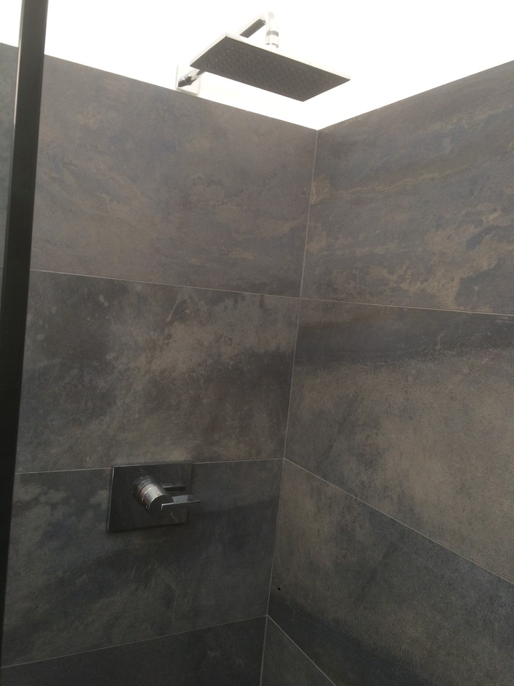 This is an example of a medium sized contemporary shower room bathroom in Orange County with flat-panel cabinets, medium wood cabinets, an alcove shower, a two-piece toilet, grey tiles, slate tiles, grey walls, slate flooring, a vessel sink, engineered stone worktops, grey floors and a hinged door.