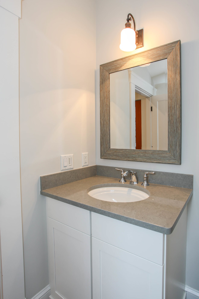 Idées déco pour une petite salle de bain craftsman avec des portes de placard blanches, un placard à porte affleurante, WC à poser, un carrelage gris, un mur gris, un lavabo encastré et un plan de toilette en granite.