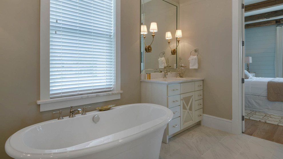 Large beach style ensuite bathroom in Miami with flat-panel cabinets, white cabinets, a freestanding bath, white tiles, stone slabs, beige walls, porcelain flooring, a submerged sink, marble worktops and an alcove shower.
