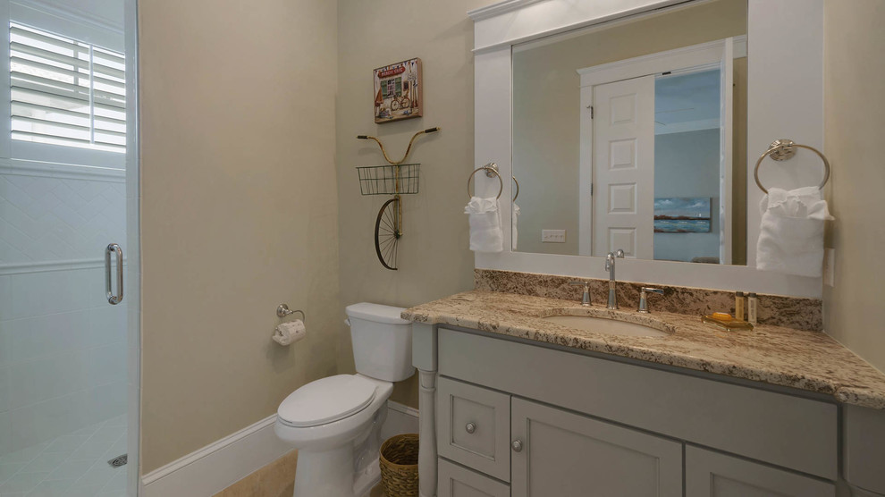 This is an example of a medium sized nautical shower room bathroom in Miami with recessed-panel cabinets, white cabinets, an alcove shower, a two-piece toilet, beige tiles, stone slabs, beige walls, ceramic flooring, a submerged sink and granite worktops.