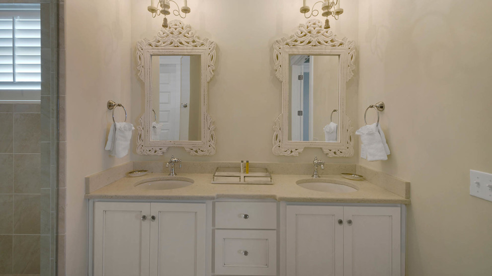Example of a mid-sized beach style master beige tile and stone slab porcelain tile bathroom design in Miami with recessed-panel cabinets, white cabinets, a two-piece toilet, beige walls, an undermount sink and solid surface countertops